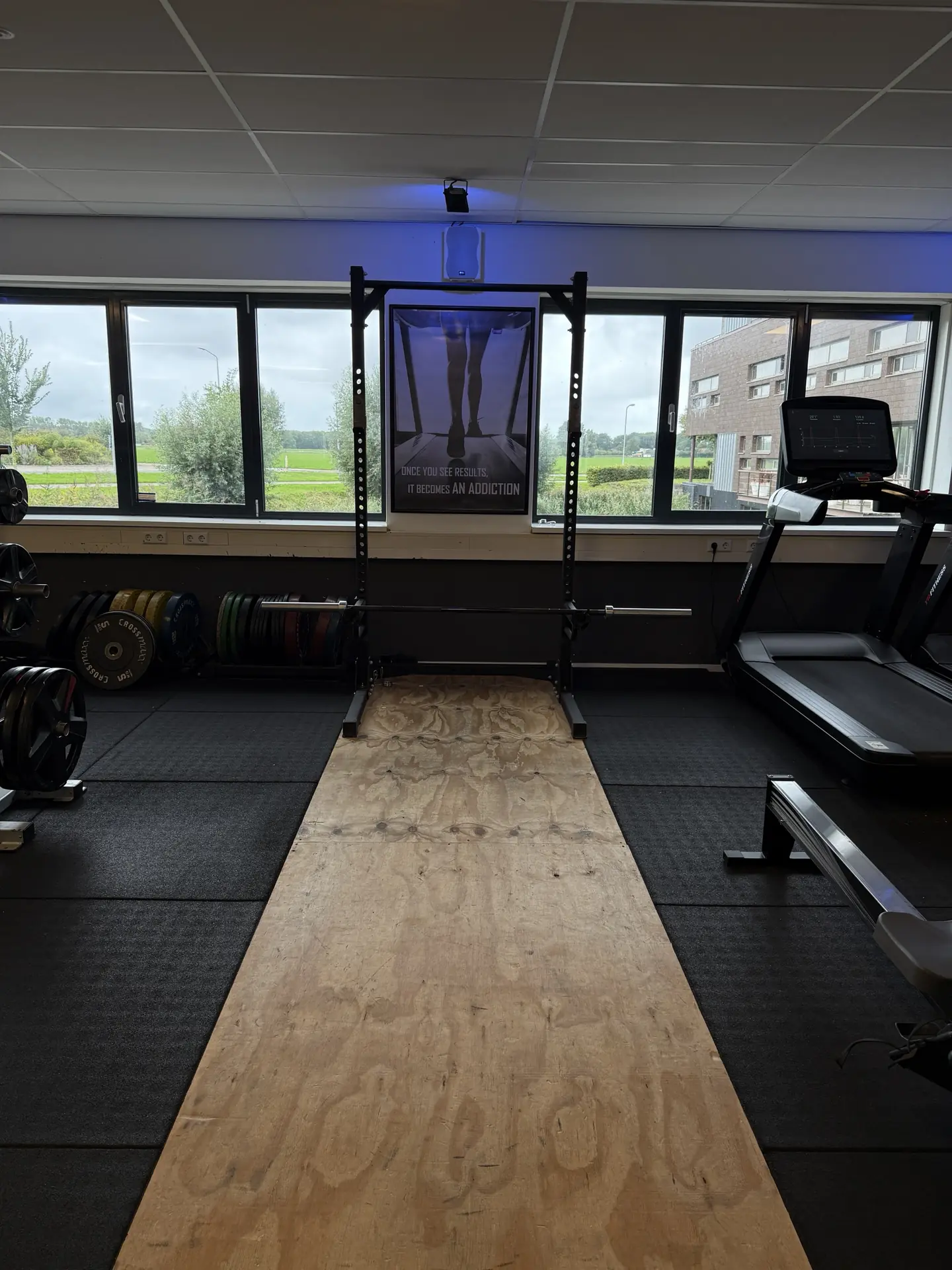 Squat rack met halterstang, bumper plates en tilplateau bij Fitcenter Warmenhuizen